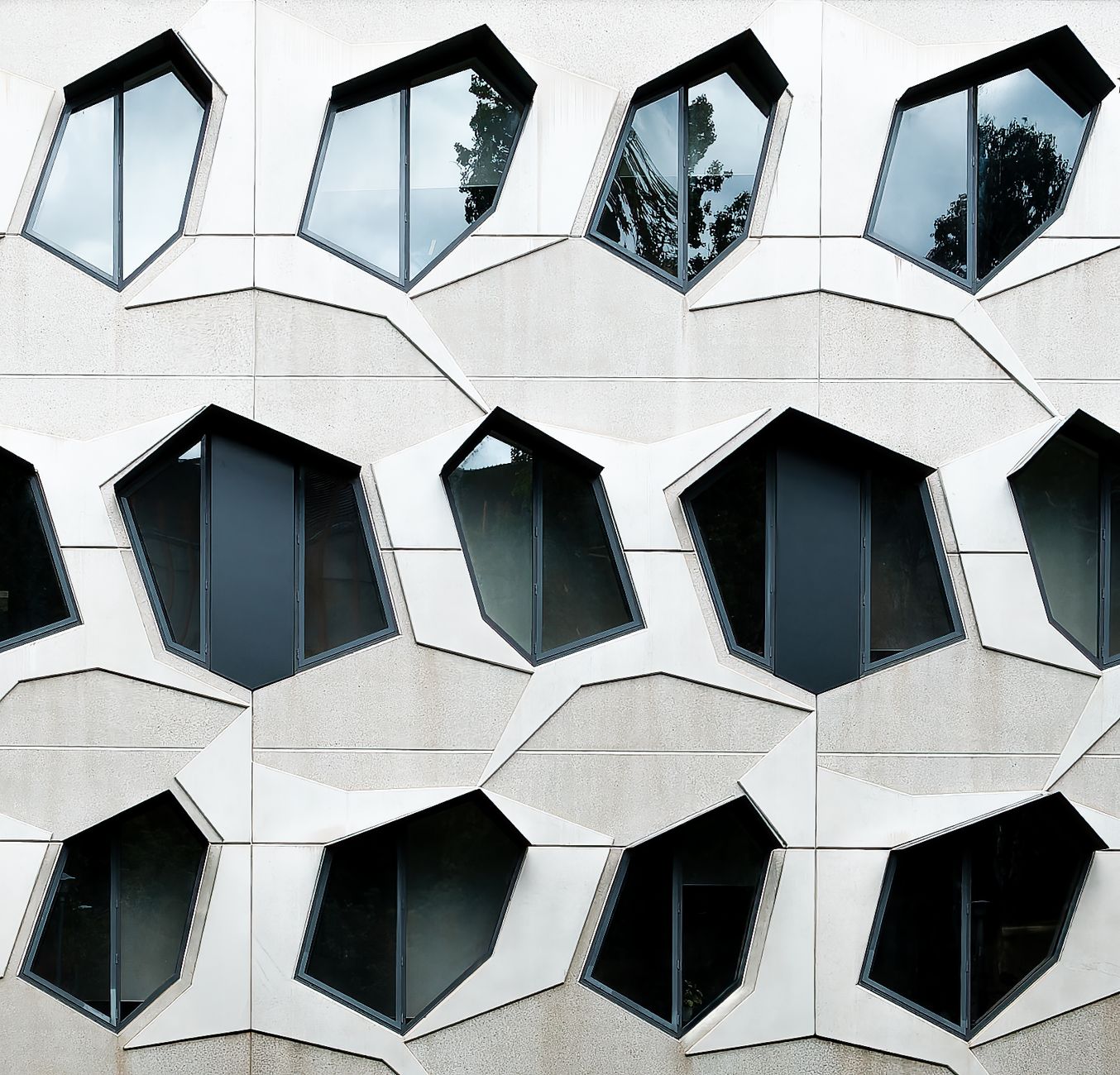 Modern geometric facade with unique windows reflecting sky in Canberra, Australia.
