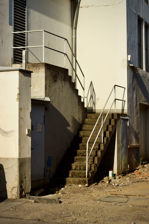 Free A sunlit exterior staircase in a gritty urban alleyway, casting shadows. Stock Photo