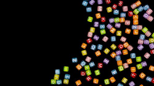 Free Vibrant colorful acrylic alphabet beads scattered on a black background. Stock Photo