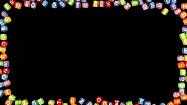 Colorful alphabet blocks forming a border on a black background with copy space.