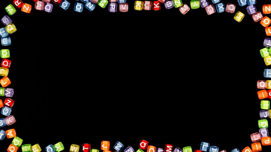 Colorful alphabet blocks forming a border on a black background with copy space.