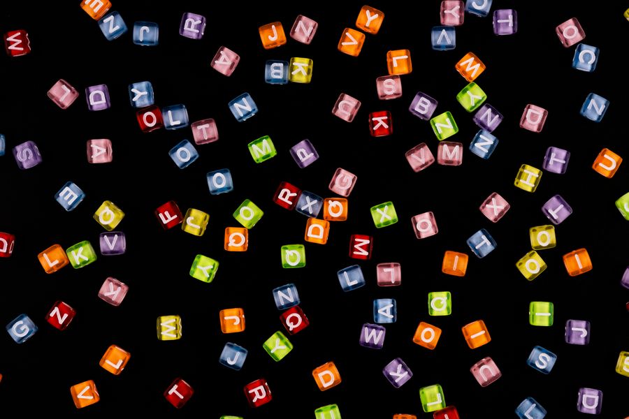 Scattered colorful alphabet beads against a dark backdrop, perfect for educational themes.