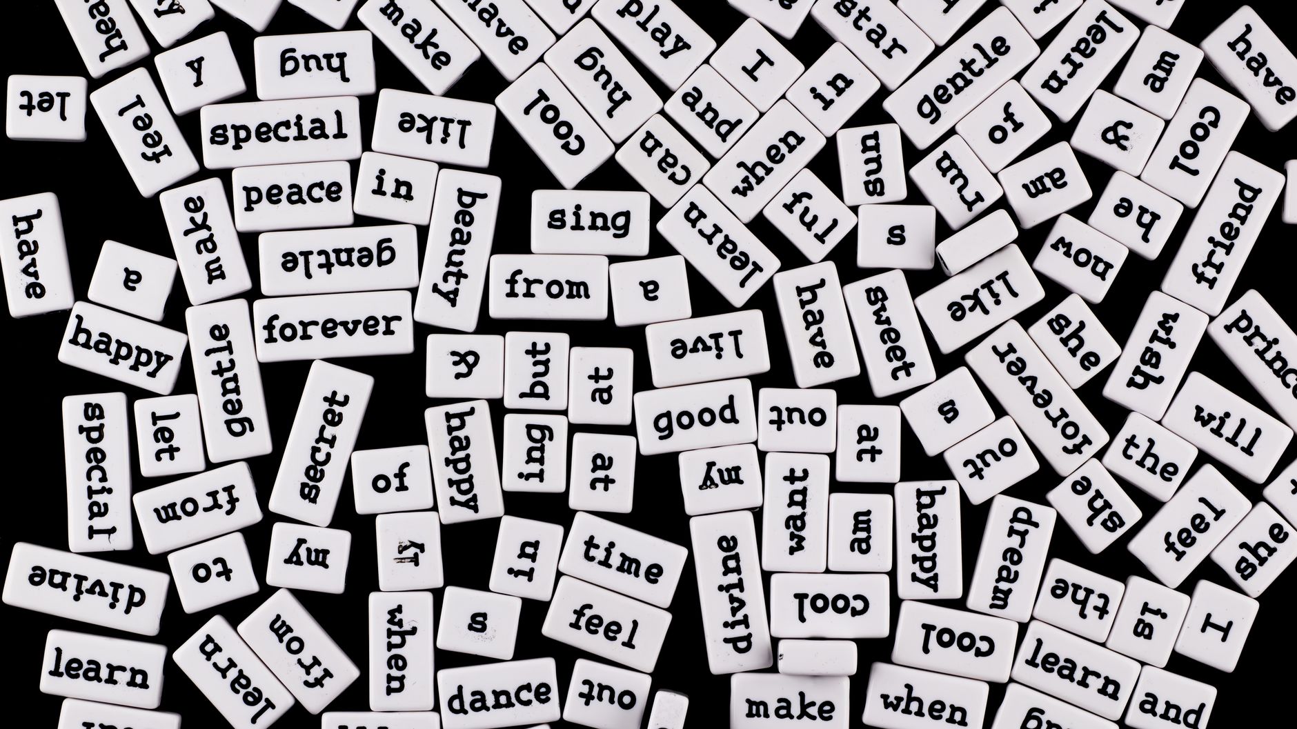 A collection of scattered word tiles on a black surface, creating a chaotic word jumble.