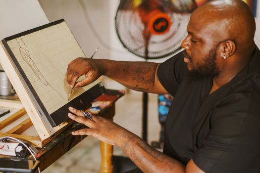 An artist sketches on a canvas in a creatively cluttered studio.