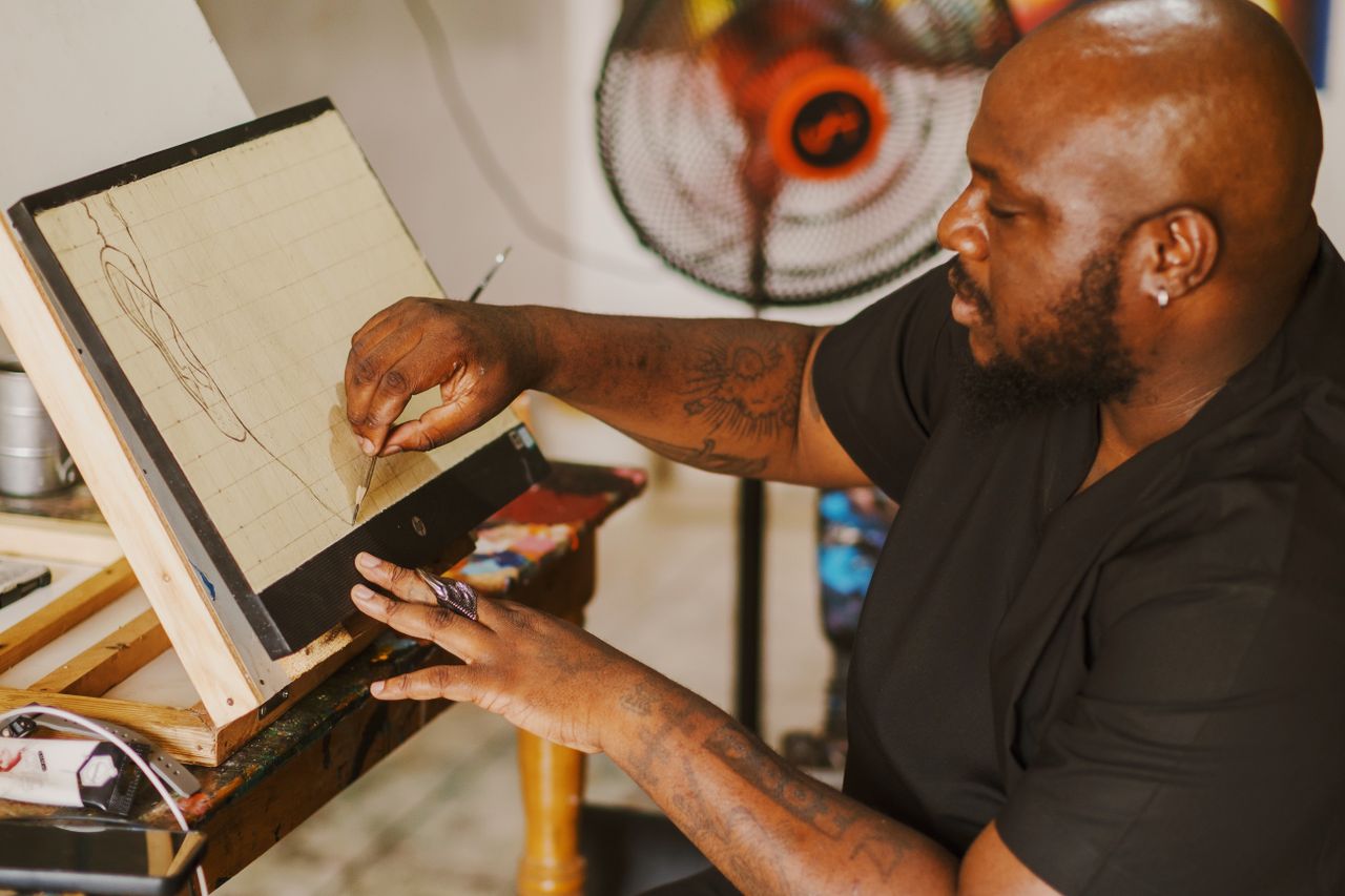 an artist sketches on a canvas in a creatively cluttered studio