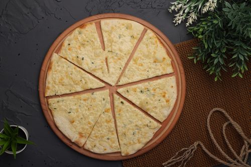 Free Freshly baked garlic flatbread sliced on a round wooden board with herbs. Stock Photo