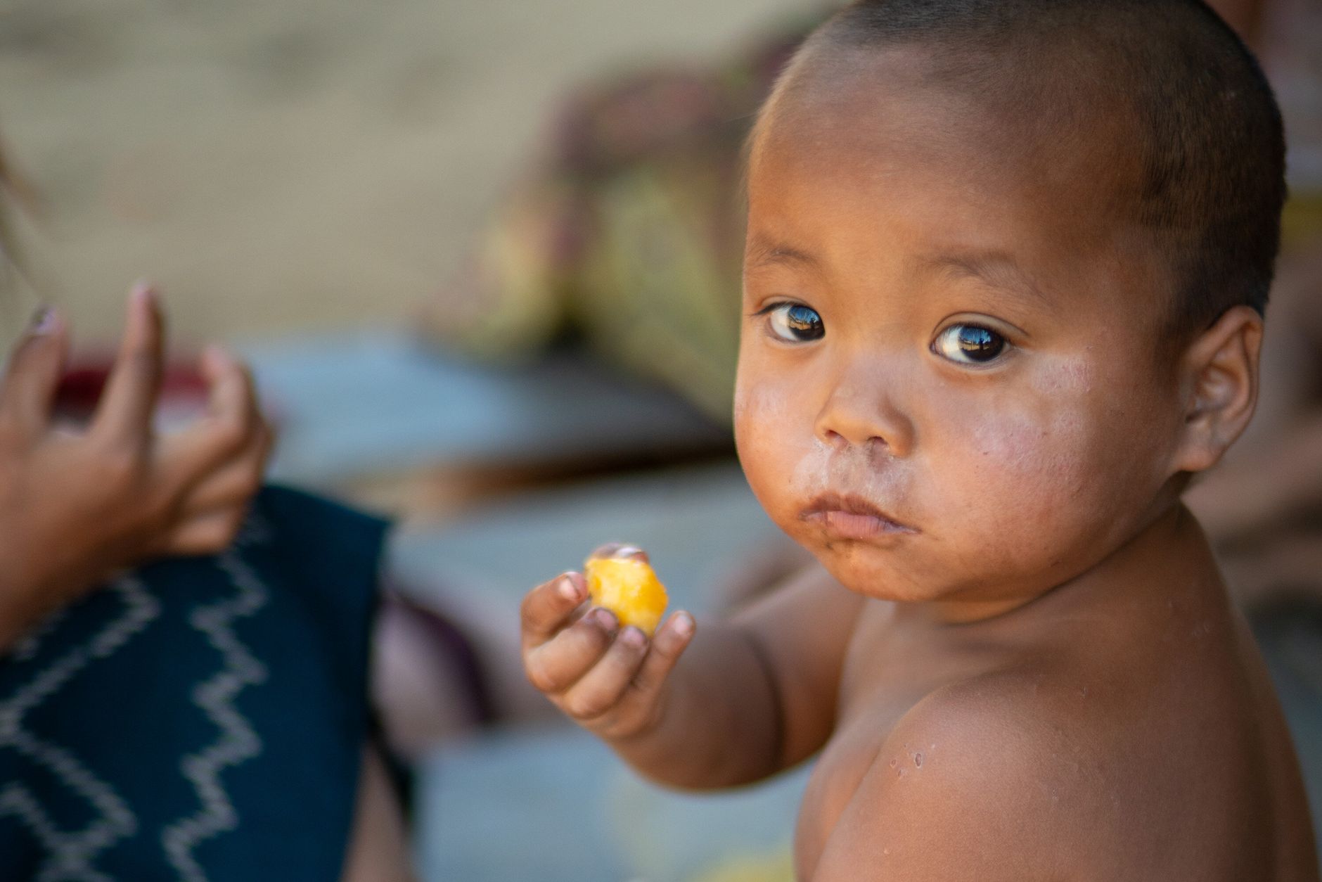 A child enjoying a piece of fruit, showcasing rural life in Laos.