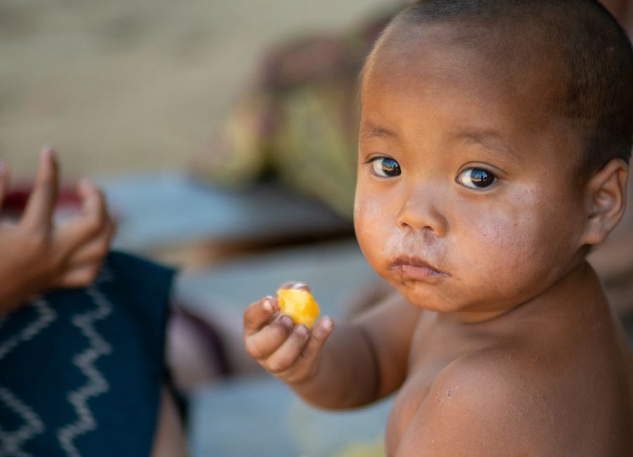 A child enjoying a piece of fruit, showcasing rural life in Laos.