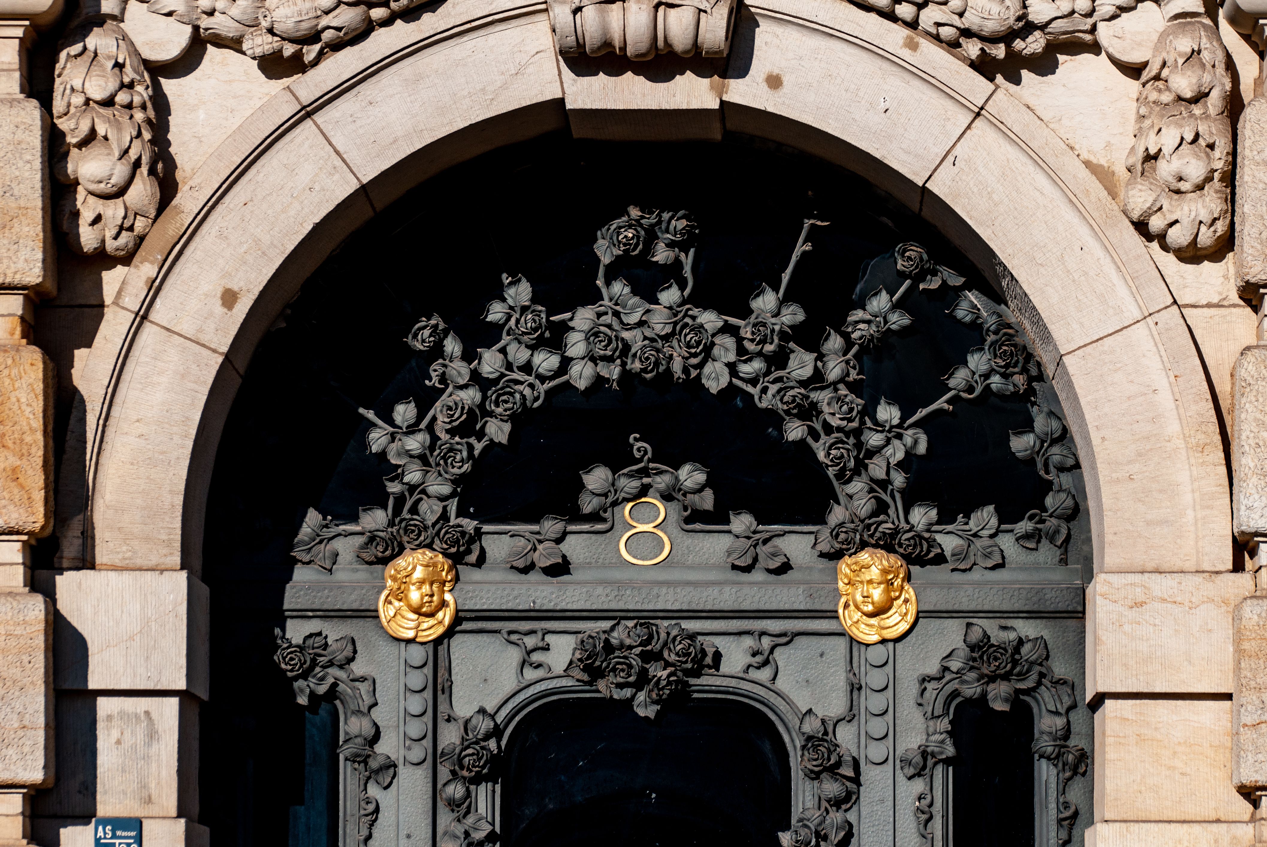 An intricately designed arched doorway with floral and lion motifs, featuring architectural details and the number 8.
