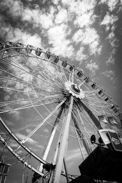 Free Artistic view of a ferris wheel captured in monochrome against a cloudy sky. Stock Photo