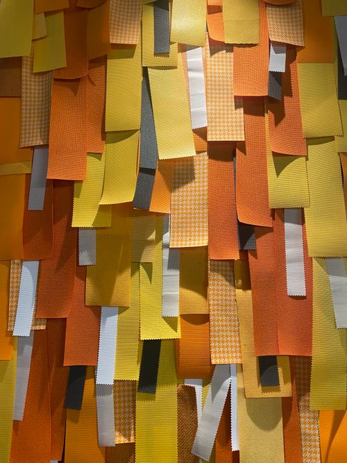 Free An artistic display of overlapping fabric strips in vibrant orange, yellow, and gray hues. Stock Photo