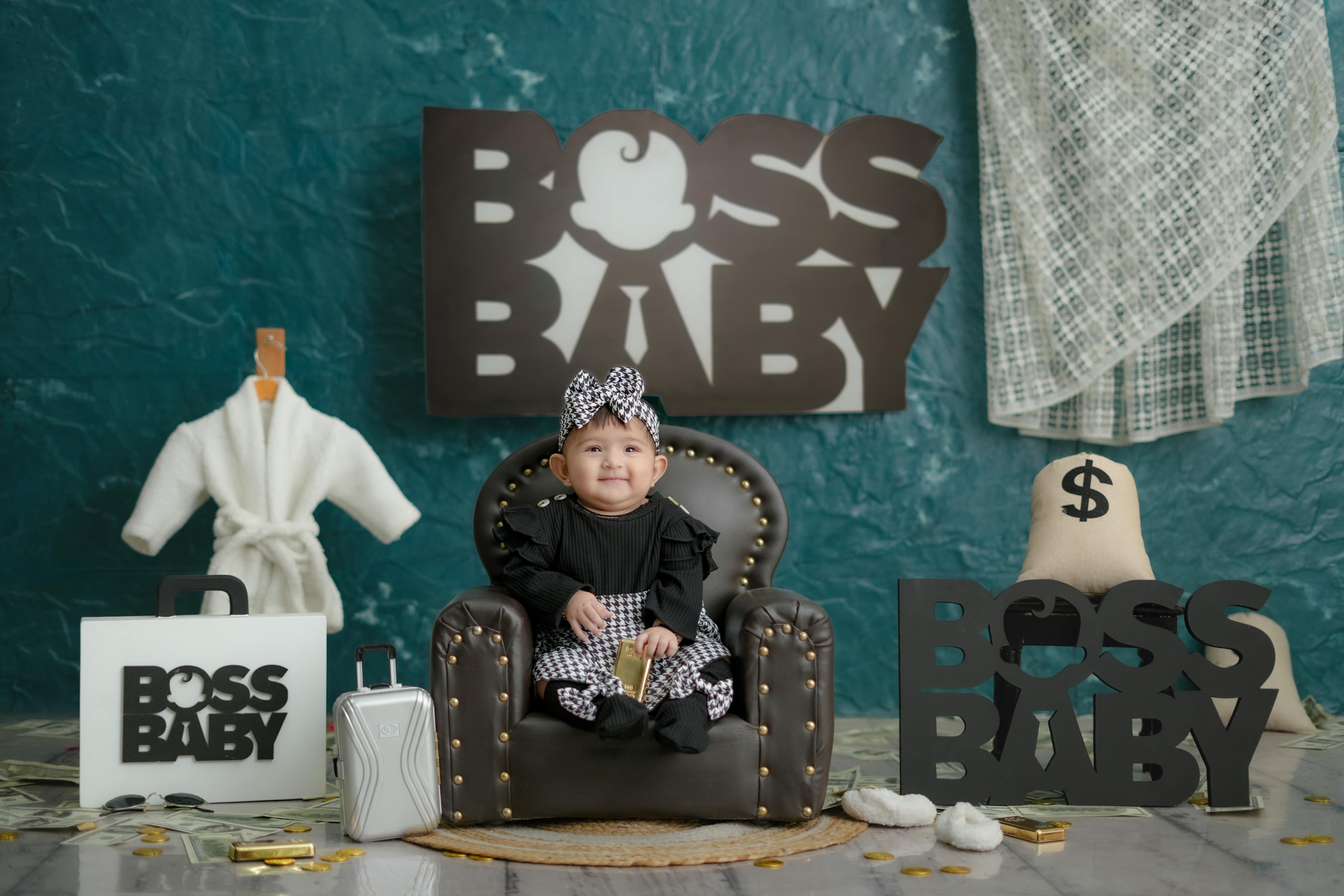 Cute baby in luxury themed setting with boss baby signs, money, and luxury items.