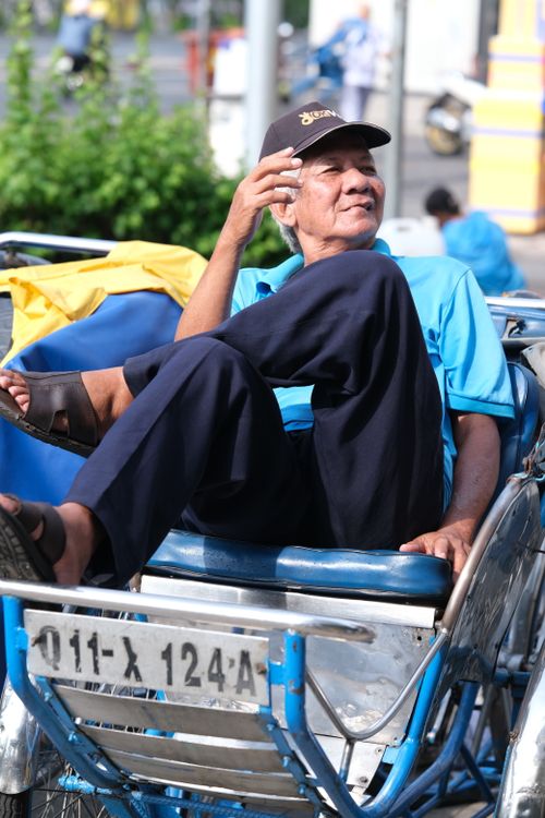 Free A rickshaw driver in casual attire enjoys a relaxing break on a sunny day. Stock Photo
