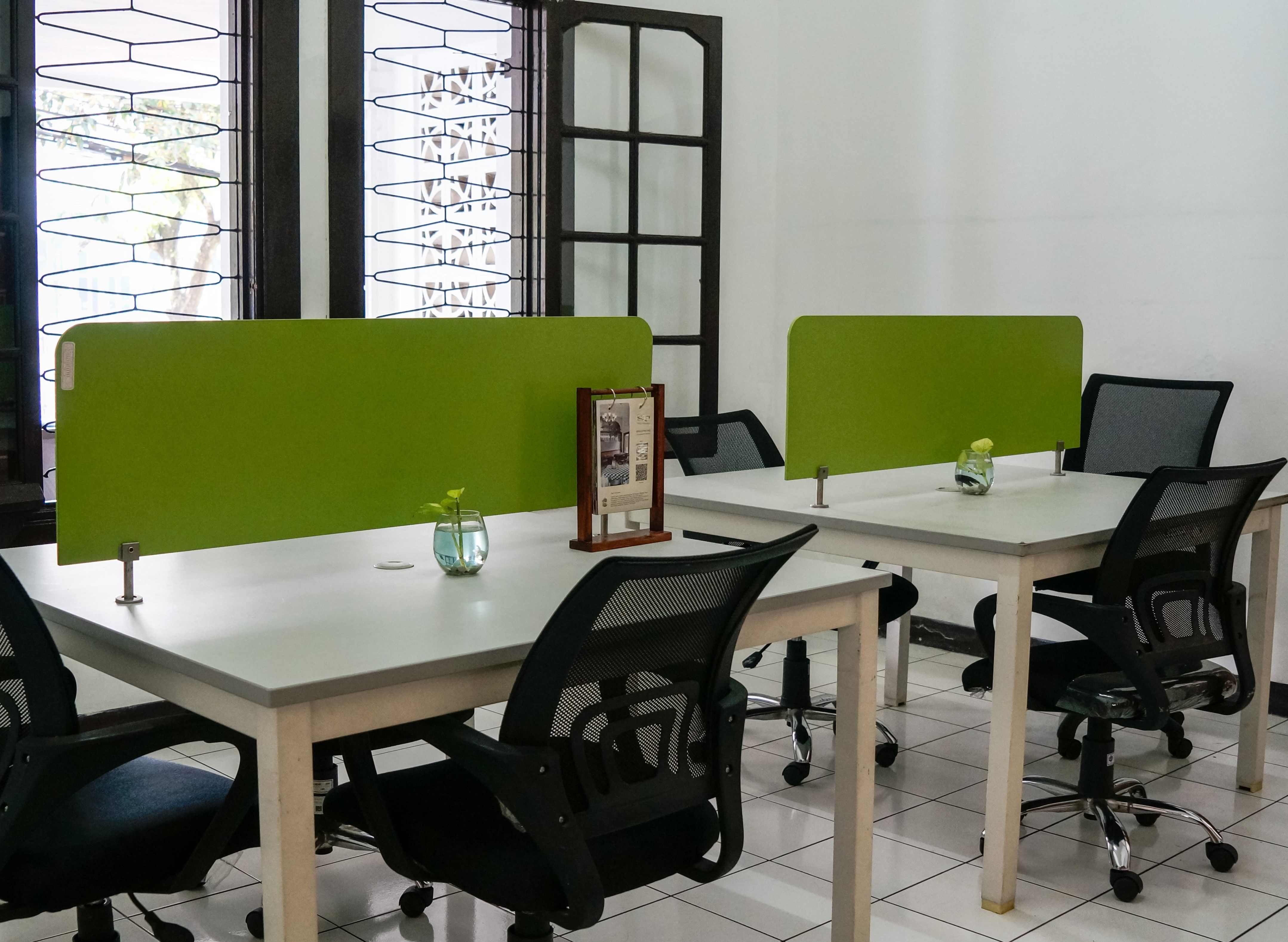 Neat and modern co-working office space featuring green dividers and ergonomic chairs.