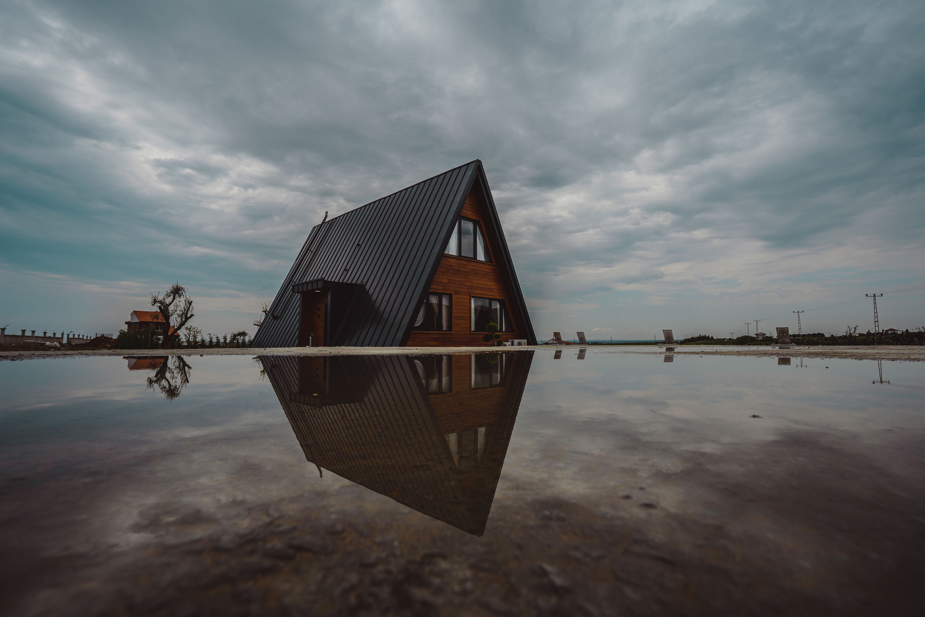 A-Frame House with Reflective Water and Moody Sky · Free Stock Photo