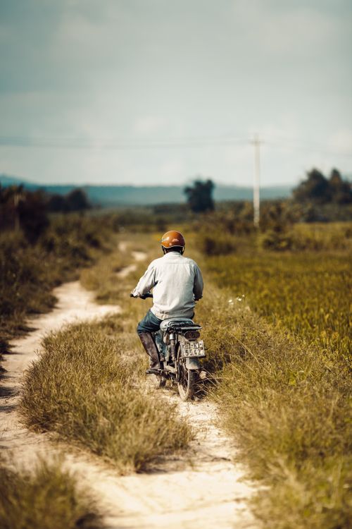 Free A person rides a motorcycle along a grassy trail in rural Kon Tum, capturing everyday life in Vietnam. Stock Photo