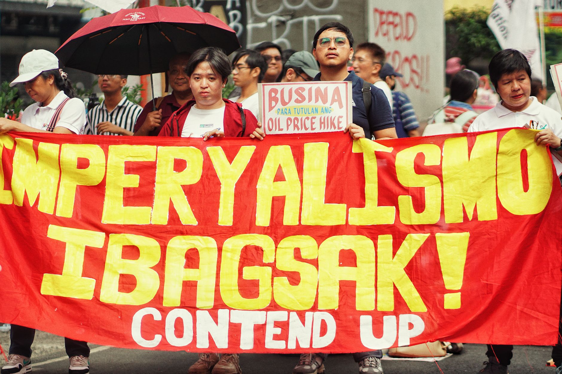Protesters holding a bold anti-imperialism banner during a street demonstration.