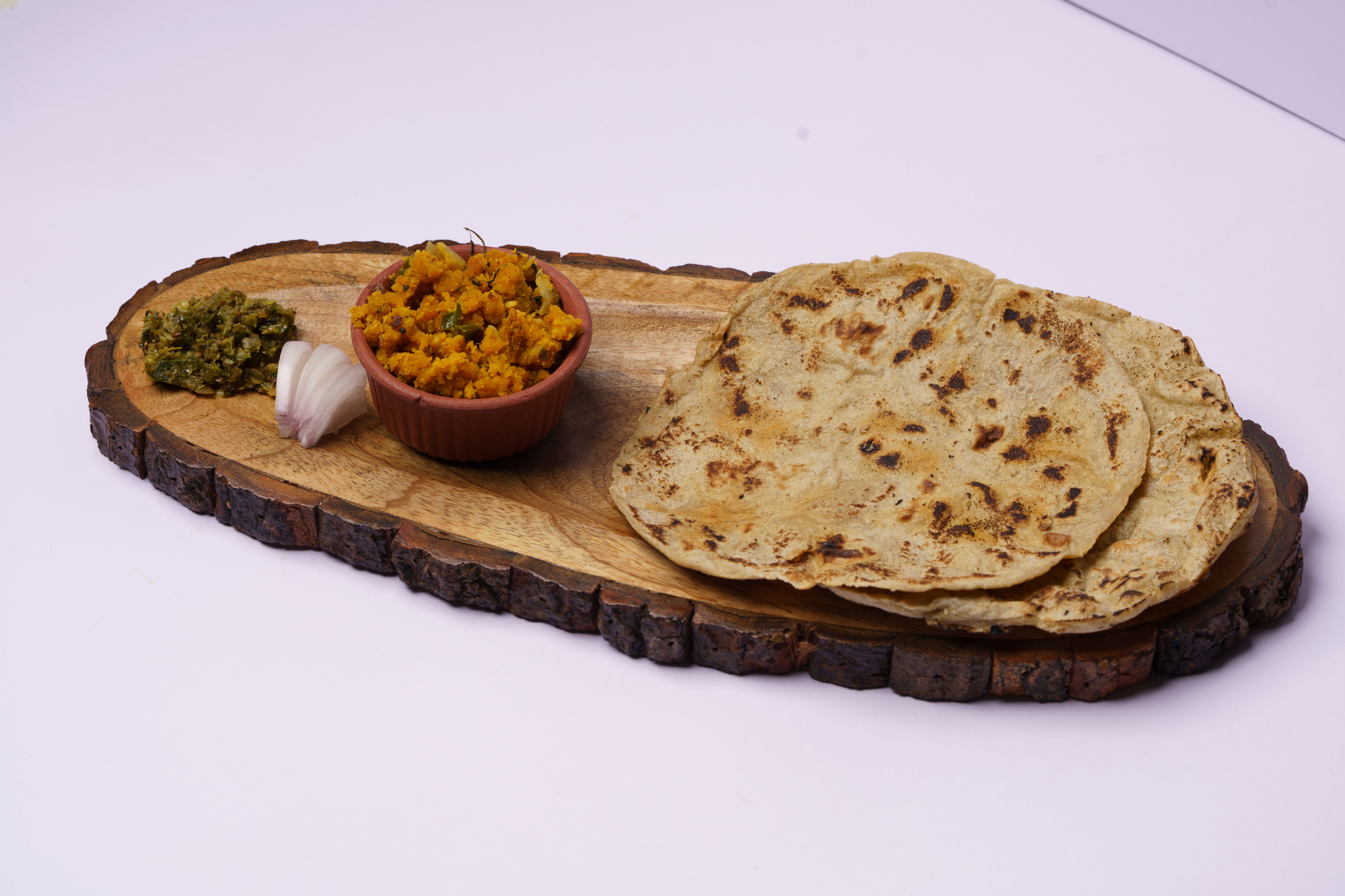 Delicious Indian flatbread with side dishes served on a rustic wooden platter.