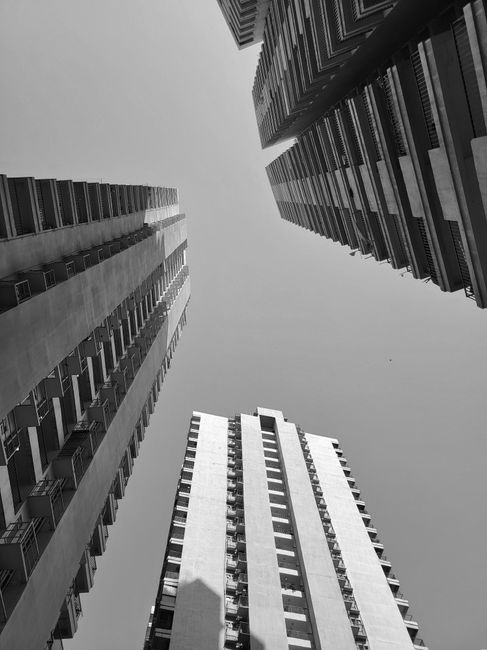 Black and white photo of towering skyscrapers viewed from below, creating a dramatic urban landscape.