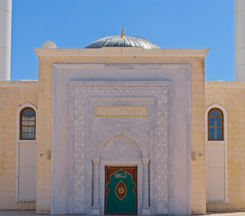 Free Elegant facade of a mosque with a dome and decorative arches under a clear blue sky. Stock Photo