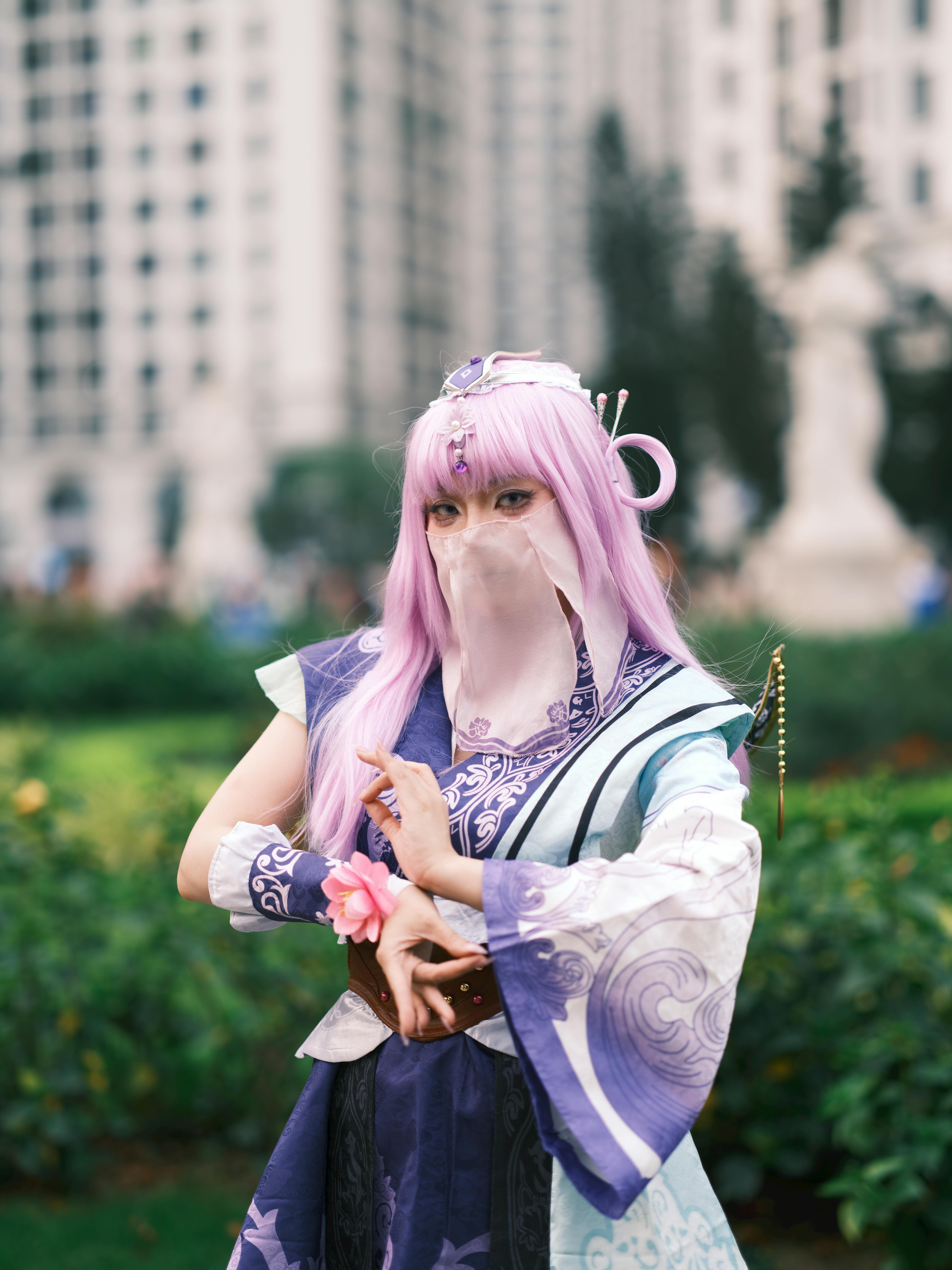 A cosplayer in intricate costume with purple accents poses in an outdoor setting in Vietnam.