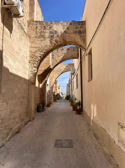 Free Explore a narrow historic street with rustic stone arches and Mediterranean architecture. Stock Photo