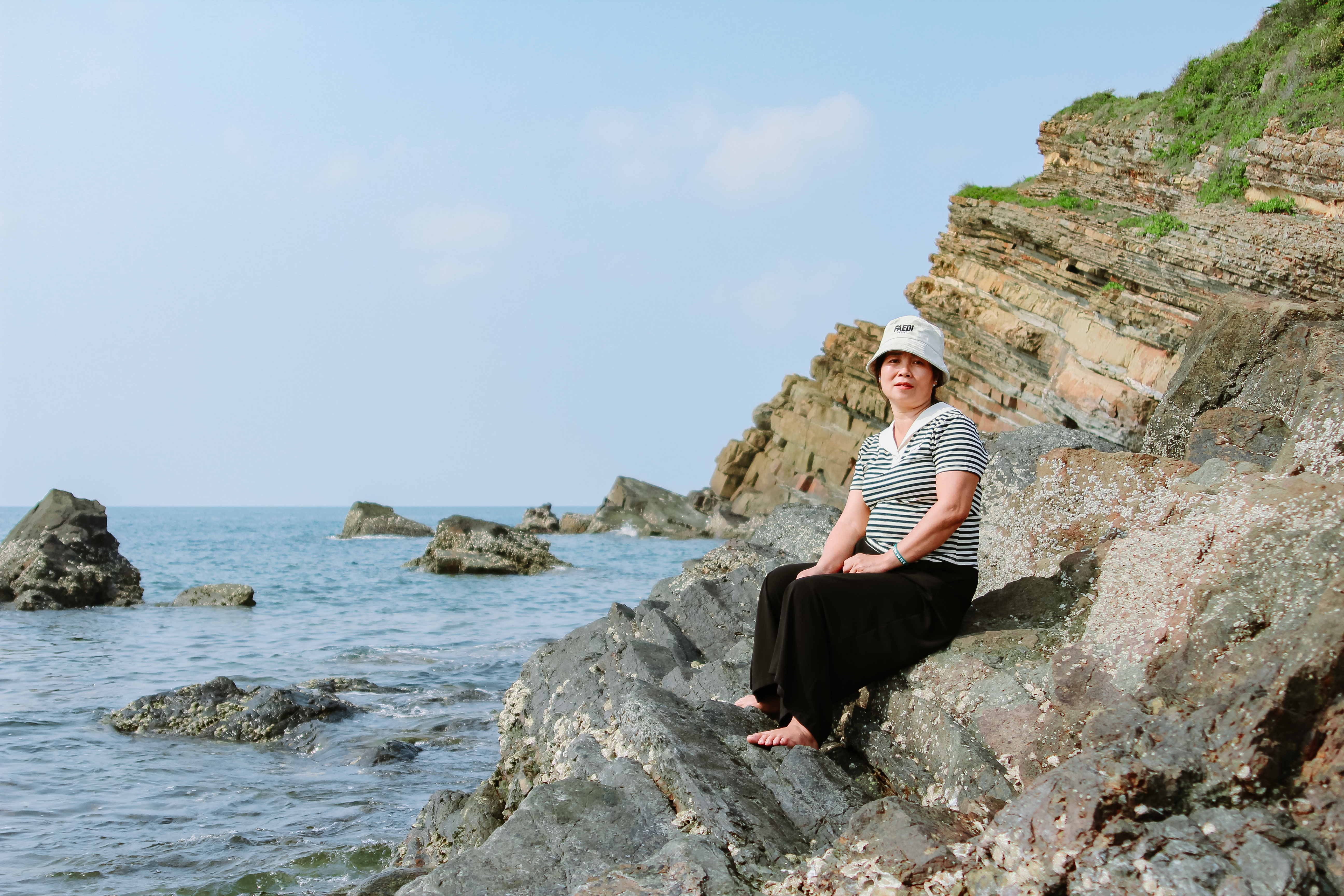 Woman Relaxing on Rocky Seaside Cliff · Free Stock Photo
