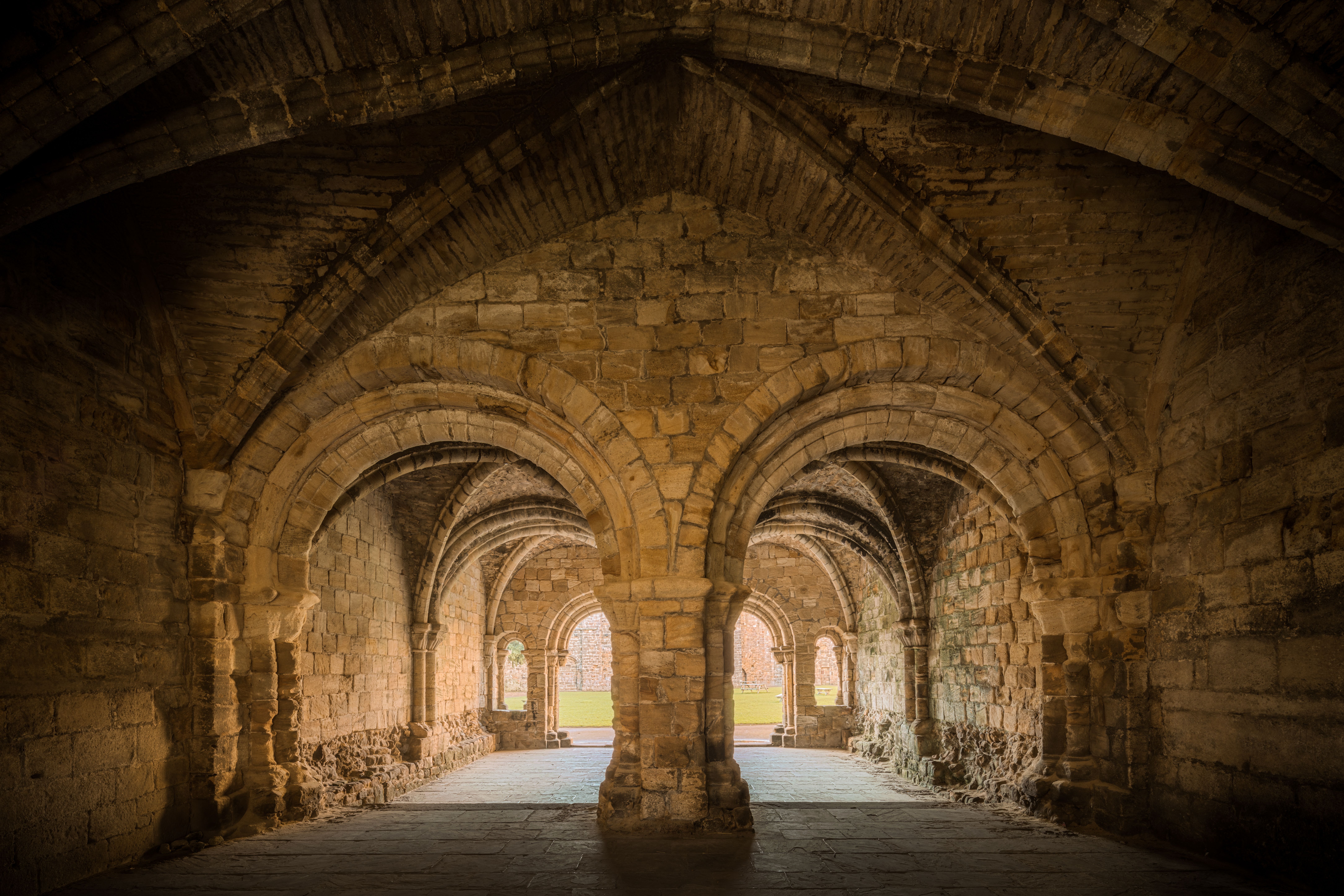 Explore the gothic arches of Kirkstall Abbey's chapter house in Leeds, England, showcasing medieval architecture.