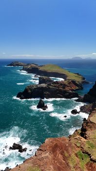 Breathtaking view of Madeira's rugged coastline with clear blue skies and vibrant ocean.