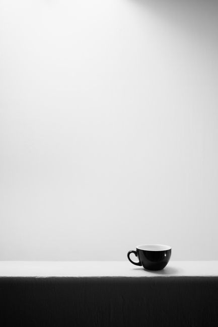 A minimalist black and white photograph of a coffee cup with ample copyspace.