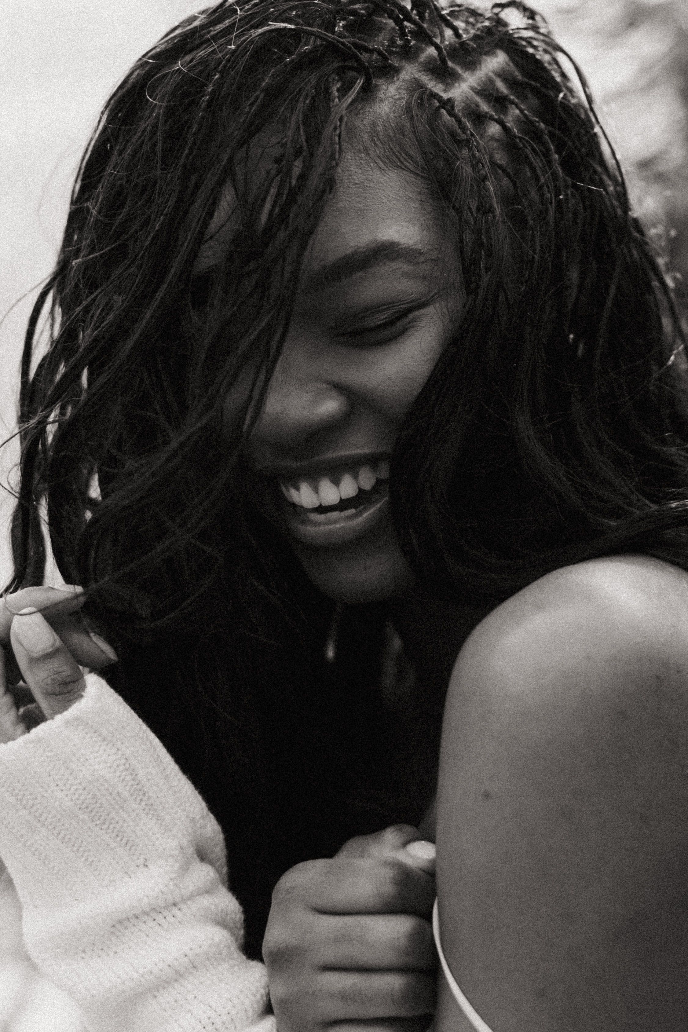 Candid black and white photo of a woman smiling joyfully, embodying happiness and warmth.