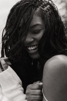 Candid black and white photo of a woman smiling joyfully, embodying happiness and warmth.