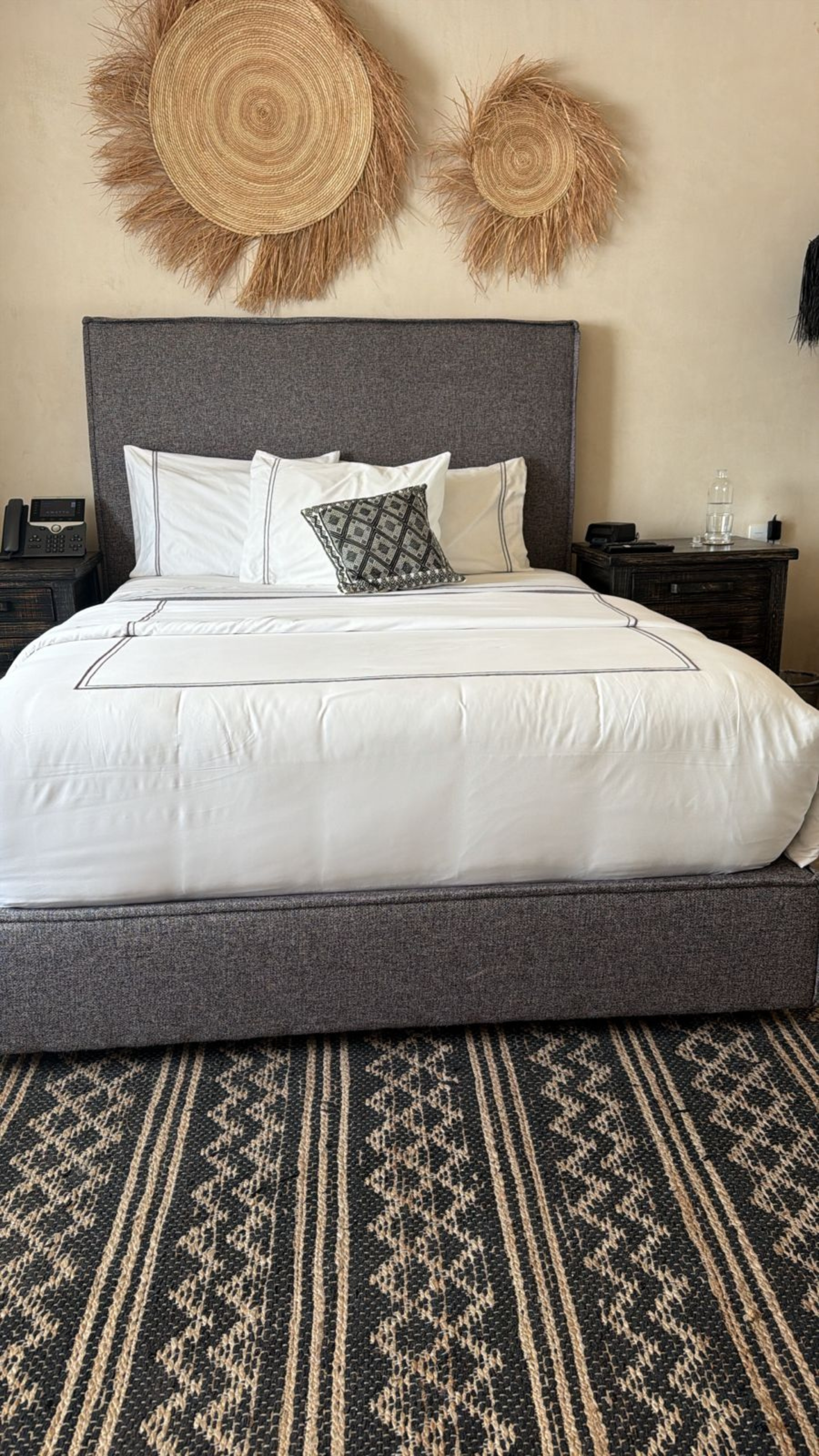 Bedroom with grey upholstered bed, patterned floor rug and restrained modern decor