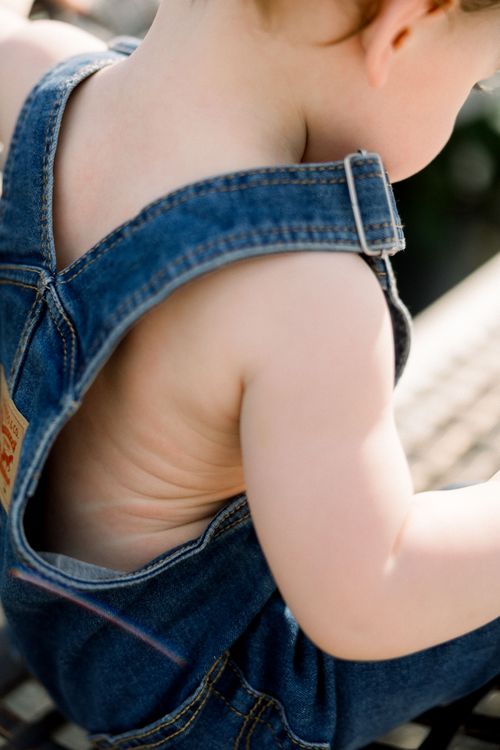 Free Cute toddler wearing denim overalls enjoying the summer outdoors. Stock Photo