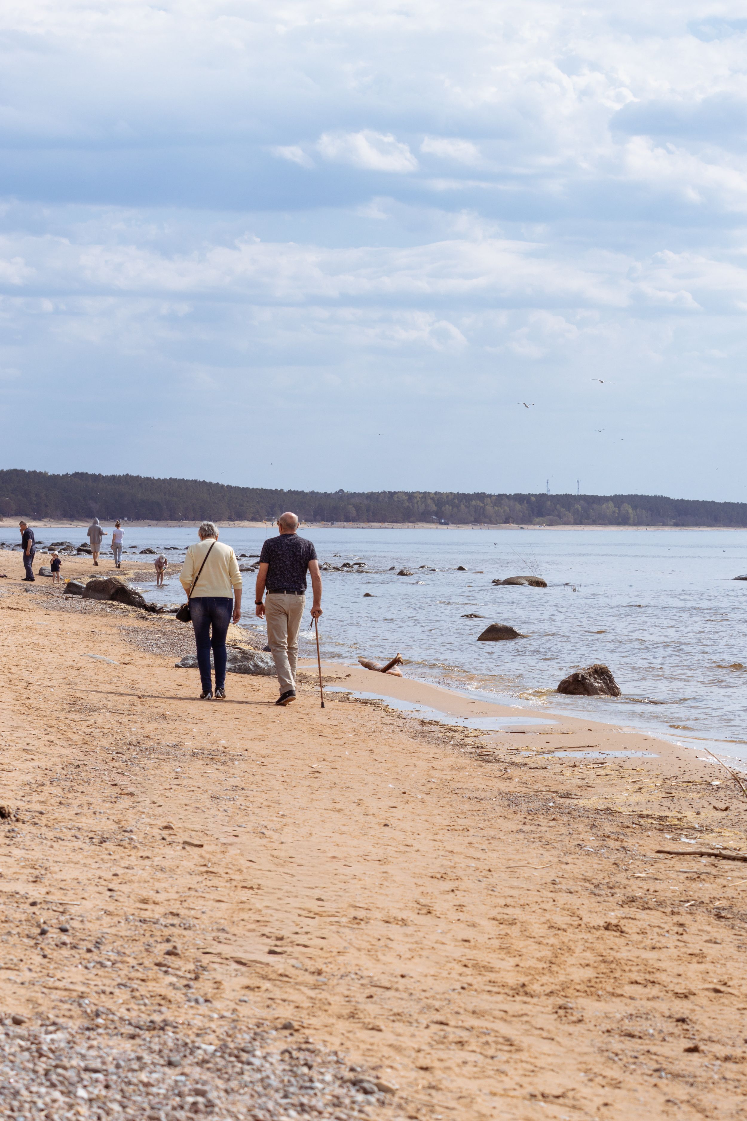 A peaceful spring day with people walking along the serene Saulkrastu beach in Latvia.