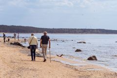 A peaceful spring day with people walking along the serene Saulkrastu beach in Latvia.