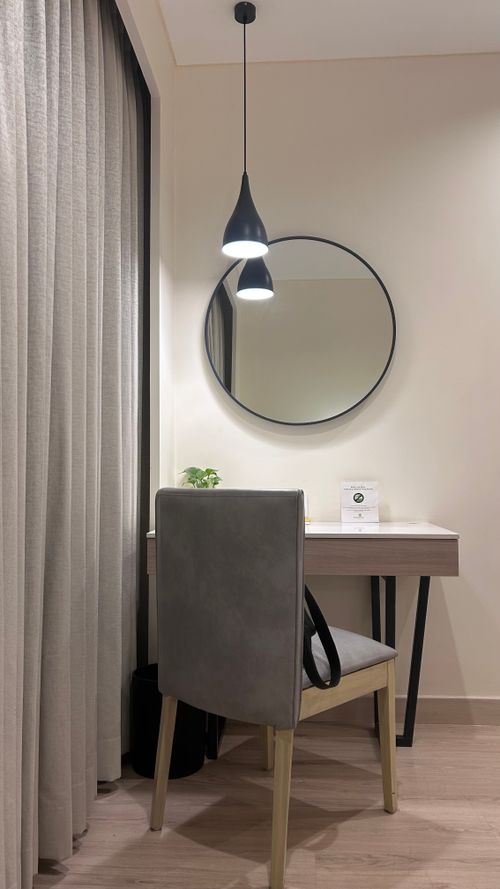 Free A stylish and cozy hotel room corner with a desk, mirror, and pendant light, showcasing minimalist decor. Stock Photo