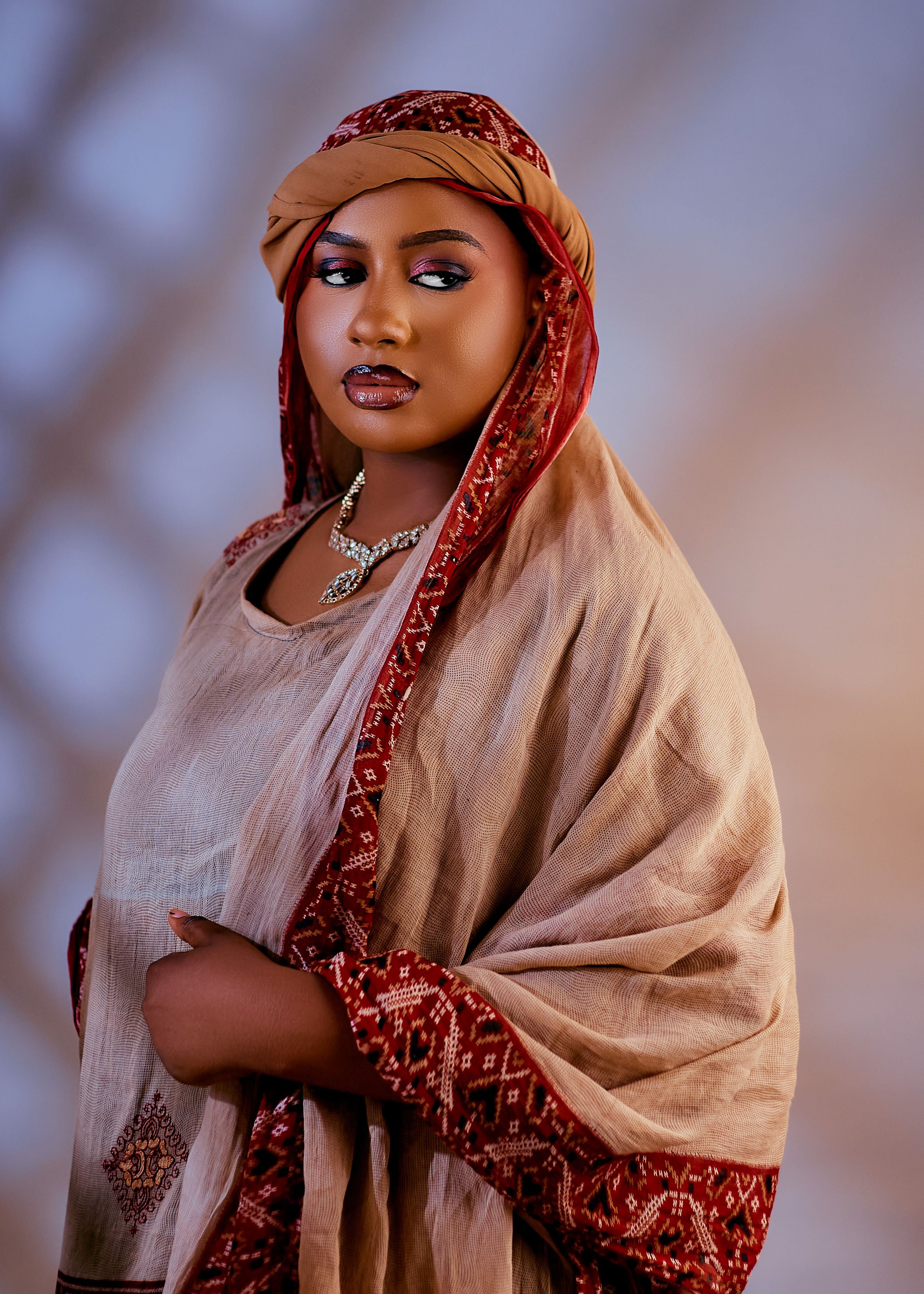 A woman in traditional clothing, featuring intricate patterns and a statement necklace, evokes a sense of cultural elegance.