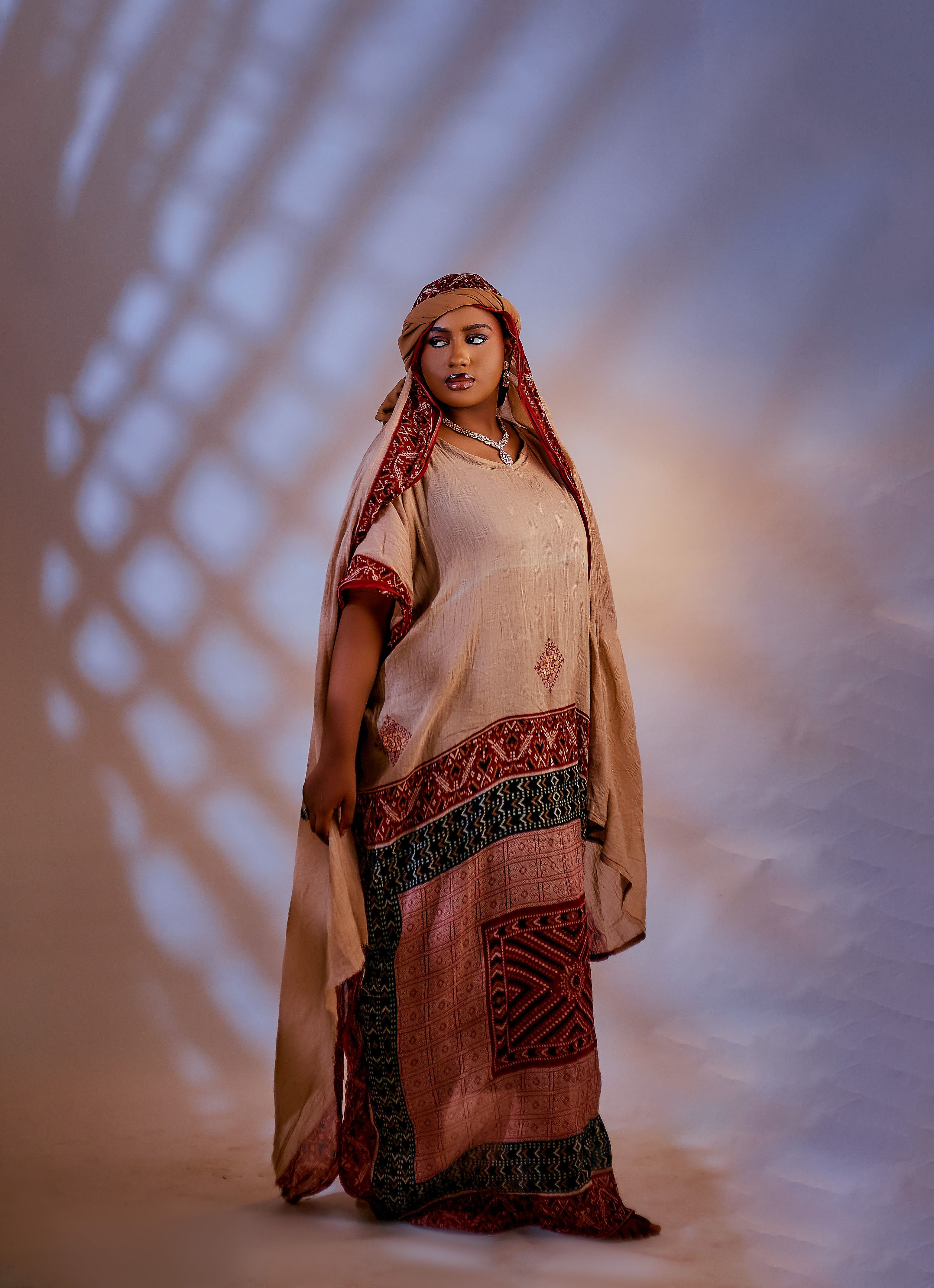 A woman poses gracefully in traditional attire with a serene backdrop, highlighting cultural beauty.