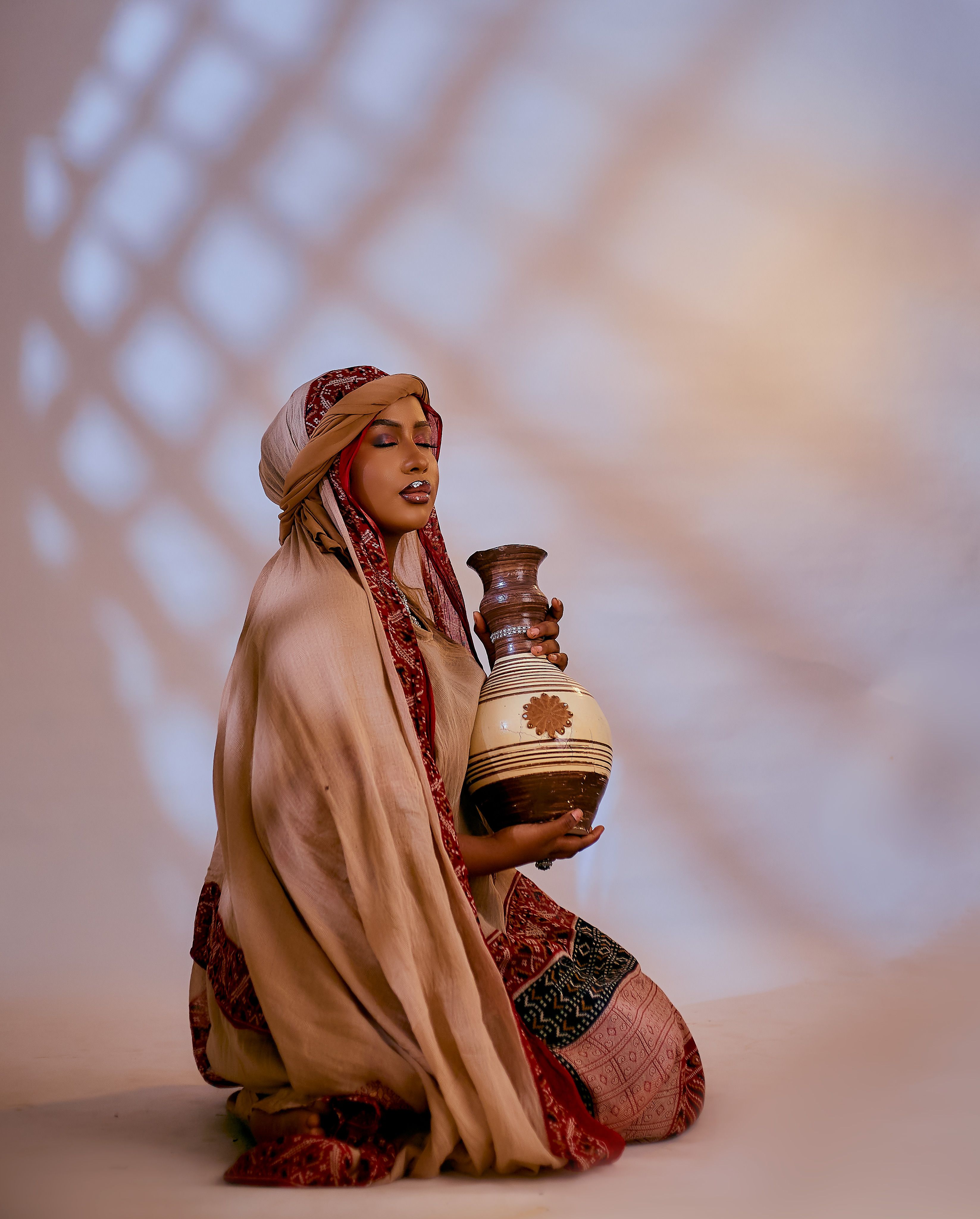 Portrait of a woman in traditional dress holding a decorated pot, indoors.