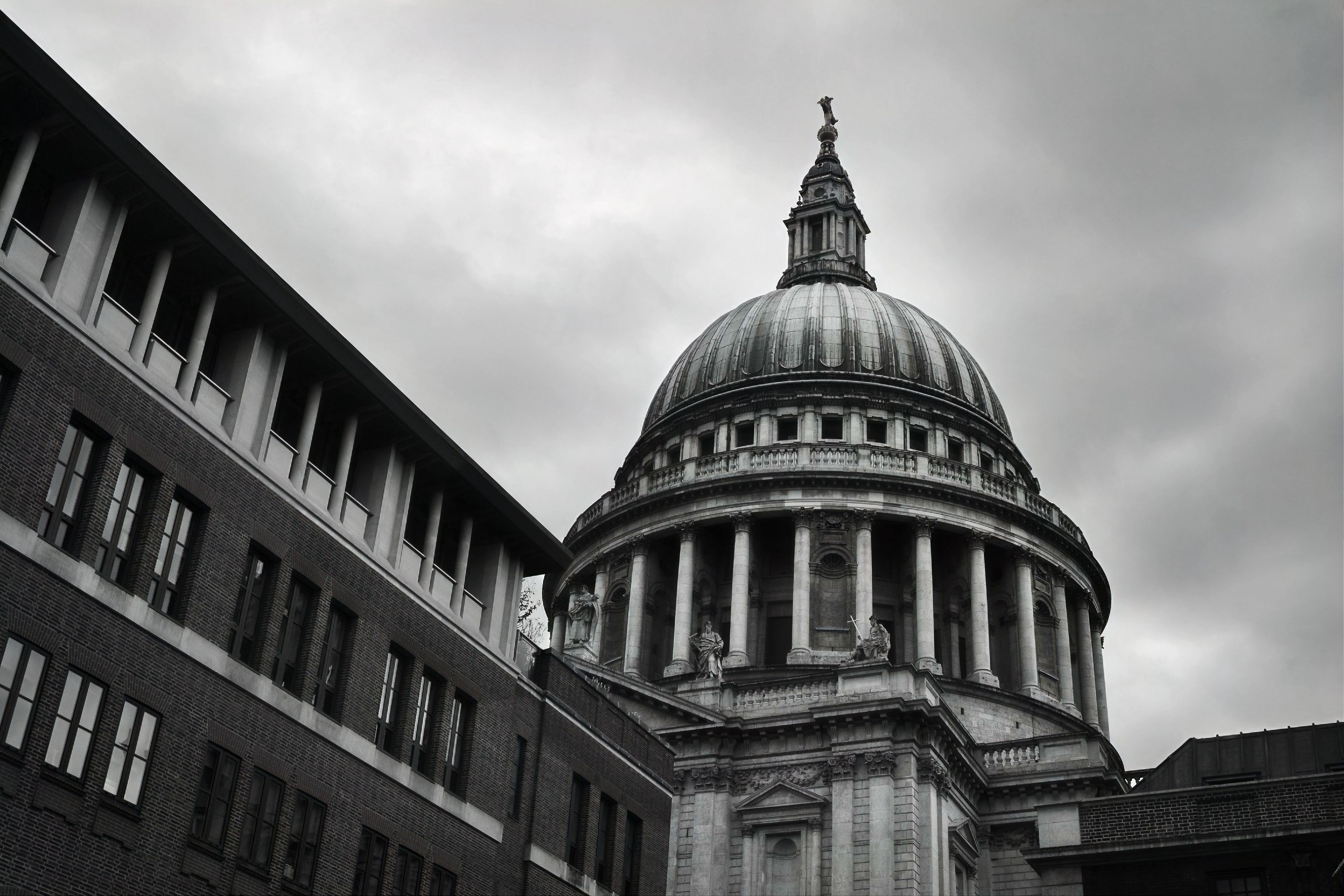 Dramatic view of St. Paul's Cathedral with overcast sky, showcasing iconic architecture.