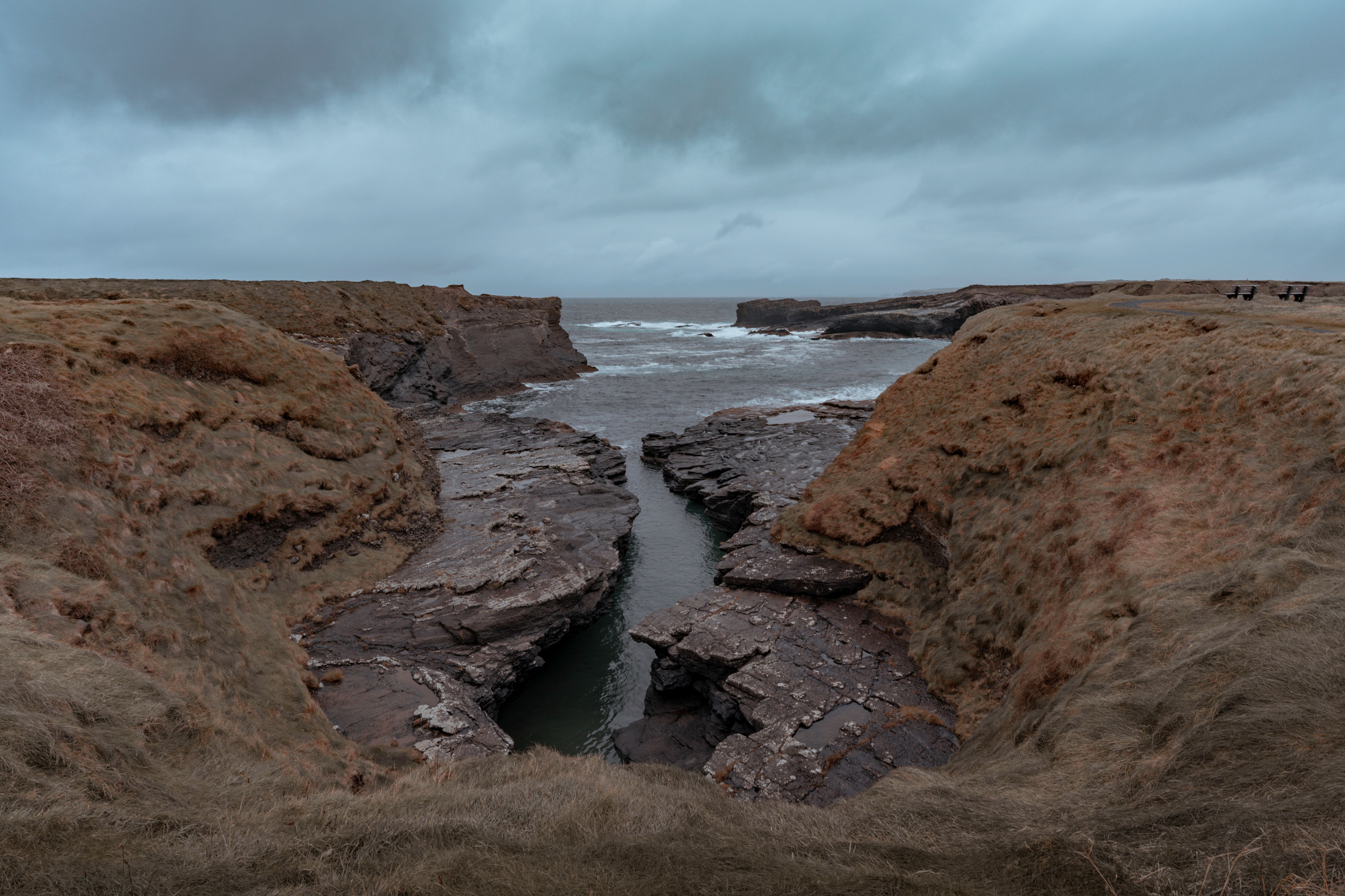 Explore a dramatic coastal scene featuring rocky cliffs and an overcast sky, perfect for nature lovers.