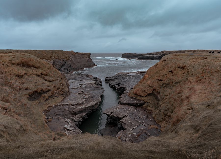 Explore a dramatic coastal scene featuring rocky cliffs and an overcast sky, perfect for nature lovers.