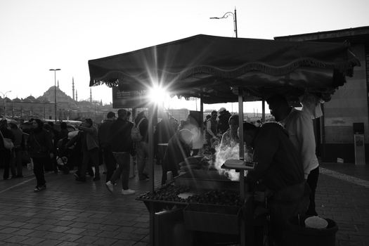 A bustling street vendor scene in İstanbul with the iconic Süleymaniye Mosque at sunset.