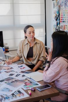 Two fashion designers discussing ideas in a creative studio with sketches.