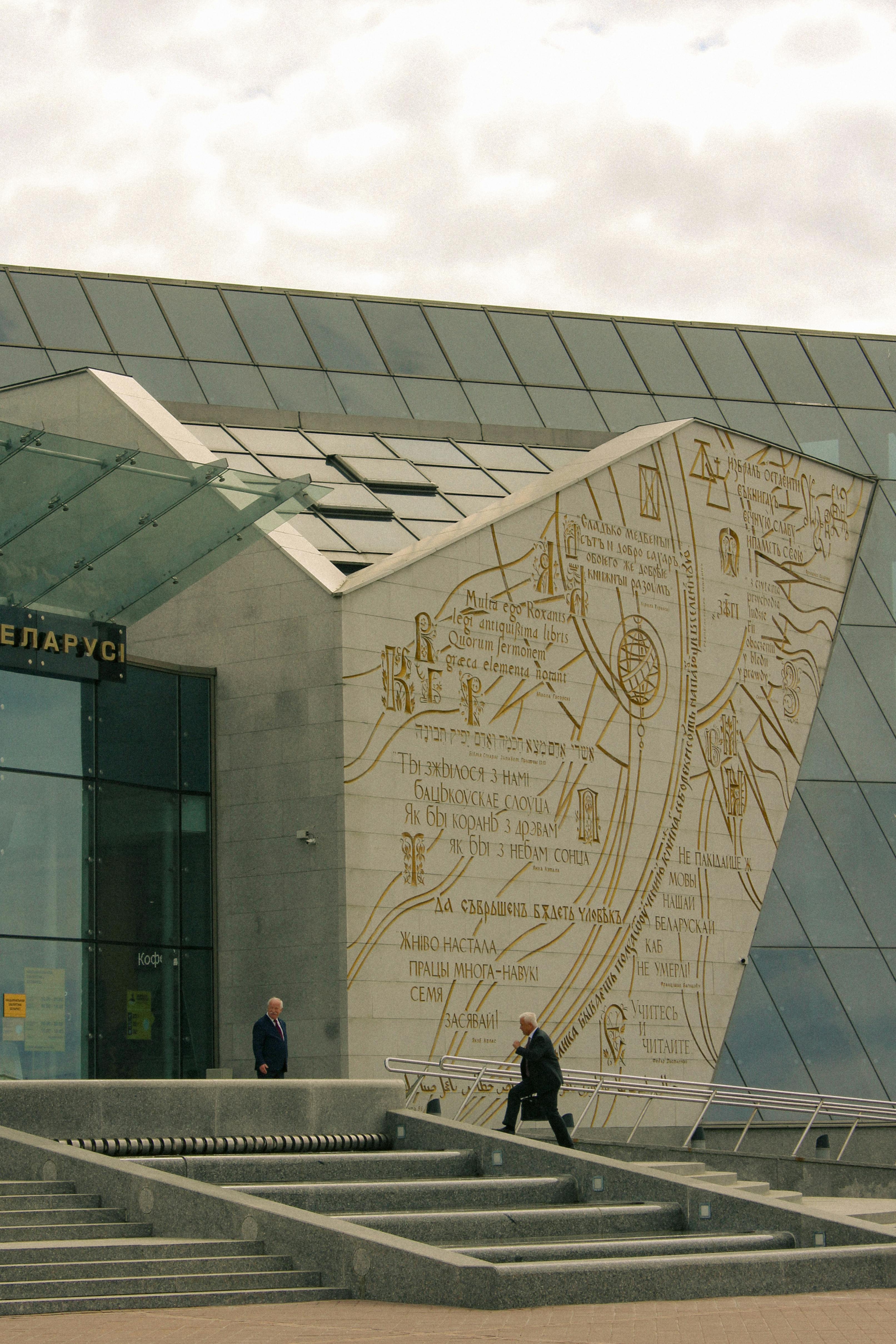 Contemporary architecture with intricate carvings and people at entrance in Belarus.