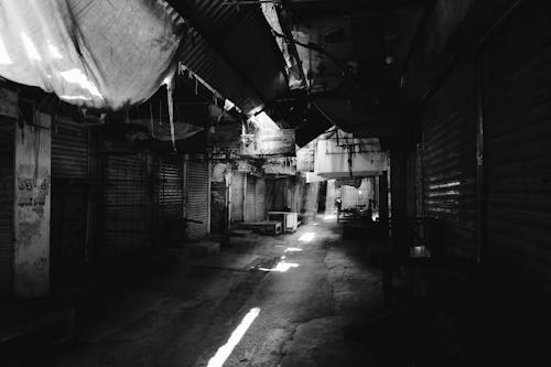 Grayscale Photography of a Walkway Between Closed Business Establishments