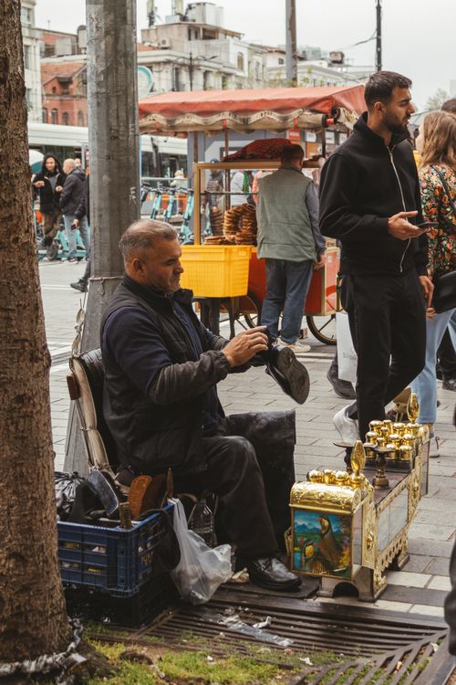 Free A shoe shiner works diligently in a lively marketplace scene, capturing urban life. Stock Photo