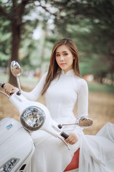 一位身着白色连衣裙的优雅女子，在风景优美的公园里骑着滑板车