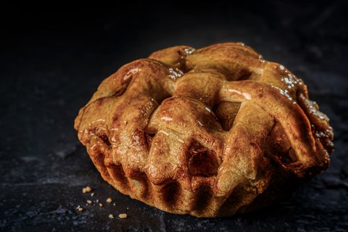 Free Close-up of a homemade apple pie with a golden glaze and flaky crust on dark surface. Stock Photo